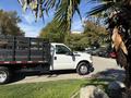 A 2016 Ford F-350 SD with a flatbed parked at an angle, featuring a white exterior and black accents