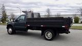 A green 2008 Ford F-450 SD flatbed truck with a large open bed and dual rear wheels parked at an angle