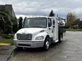 A white 2005 Freightliner M2 106 truck with a flatbed and multiple lights on the roof is parked and facing the viewer