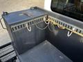 A metal storage box with a chain and hooks attached to the inside of a truck bed with a textured floor