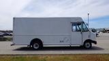 A side view of a white 2011 Ford Econoline delivery truck with a boxy cargo area and large front windows