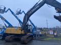 A 2014 John Deere 350G excavator with a large arm and bucket, featuring a yellow and black color scheme, positioned on tracks in a construction area