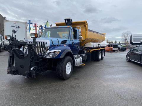 A blue 2016 International 7400 dump truck with a yellow dump bed and a snow plow attached at the front