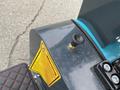 Close-up of a 2024 AGT Mini Excavator showing a warning label and a valve knob on the side of the machine