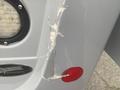 A damaged section of a 2017 Chevrolet Express showing cracks and scuff marks on the vehicle's rear side