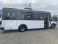 A 2018 Chevrolet Express bus with a white body and black accents featuring large windows and a side door