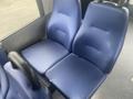 A blue upholstered two-seat configuration from a 2017 Chevrolet Express bus with armrests on either side