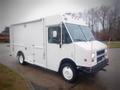 A white 2003 Freightliner MT45 Chassis with a boxy shape and large front windows featuring multiple roof lights and side access doors