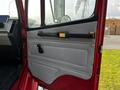 The interior door panel of a 1994 Freightliner FL80 featuring a gray fabric surface with a yellow handle and a black latch