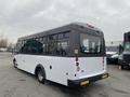 A 2017 Chevrolet Express bus with a white exterior and black accents visible from the rear showcasing large windows and rear lights