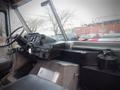 Interior of a 2003 Freightliner MT45 Chassis showing the driver's seat dashboard and controls with a black canister on the floor