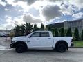 A white 2021 RAM 1500 pickup truck with a crew cab and black wheels parked on a concrete surface