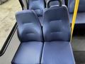 Two blue fabric seats in a vehicle interior with a yellow pole beside them