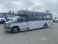 A 2017 Chevrolet Express bus in a two-tone color scheme with large windows and a wheelchair ramp on the side