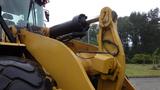 A close-up of a yellow 2019 Caterpillar 972M XE front loader showcasing its hydraulic arm and bucket mechanism