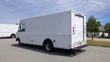 A white 2011 Ford Econoline delivery van with a boxy shape and rear roll-up door parked in a lot