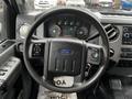 Interior view of a 2014 Ford F-550 showing the steering wheel with controls and dashboard gauges visible along with the console and gear shift