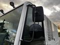 A close-up view of a side mirror attached to a white 2007 Tennant Sentinel vehicle with a black mounting arm