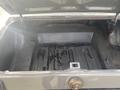 The trunk of a 1966 Ford Mustang showing a flat interior with a spare tire well and a rectangular latch in the center