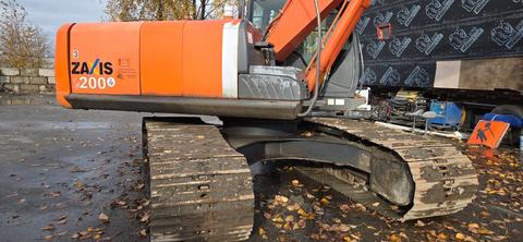 A 2006 Hitachi ZX200 excavator featuring a distinctive orange and gray color scheme with large tracked wheels and a hydraulic arm