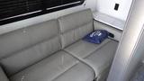 A gray sofa with a single blue cushion in a camper interior