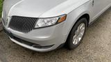 A silver 2013 Lincoln MKT with a distinctive grille and sleek design parked on a wet surface