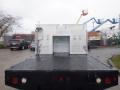 A 2009 Ford F-450 SD with a flatbed and metallic utility box positioned on the rear