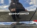 A close-up of the rear emblem on a 2023 Acura MDX showcasing the SH-AWD badge with water spots on the surface