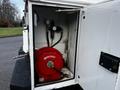 A 2017 Ford F-550 with a storage compartment containing a red reel with gauges and hoses visible inside