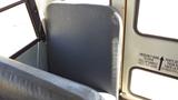 The image shows the back of a gray seat in a bus with textured upholstery and a partial view of a second seat in the foreground