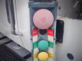 Close-up of a control panel featuring a large pink button and several colored buttons labeled STOP in red and other buttons in green and yellow