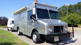 A 2005 Morgan Olson Workhorse vehicle with a metallic silver exterior featuring large front windows and an orange light on top