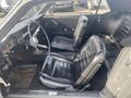 Interior of a 1966 Ford Mustang featuring two black leather bucket seats a steering wheel and classic dashboard controls