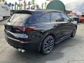 A black 2023 Acura MDX with stylish lines and a sporty design features a rear spoiler and dual exhausts