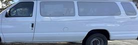 A white 2002 Ford Econoline van with a high roof and multiple windows on the side