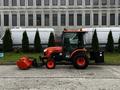 A 2018 Kubota B2650 tractor with an orange and black color scheme featuring a front-mounted snow blower attachment and a rear bucket