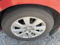 A close-up of a silver alloy wheel with a five-spoke design mounted on a tire with visible tread patterns and branding on a red Toyota Camry Hybrid