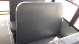 A gray vinyl bus seat backrest with a smooth surface and contoured shape designed for passenger comfort in a school bus setting