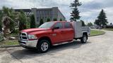 A red 2013 RAM 2500 pickup truck with a silver tool box mounted in the truck bed parked on a street