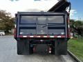 A blue 2011 International 7300 truck with a raised dump bed and chains visible on the rear panels