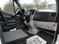 Interior view of a 2016 Mercedes-Benz Sprinter showcasing the driver's seat dashboard and controls with a black seat cover and a floor mat that says Thank You