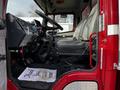 A red 1994 Freightliner FL80 interior featuring a driver's seat dashboard controls and a thank you mat on the floor