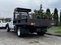 A 2015 Ford F-550 flatbed truck with a black metal bed built for carrying cargo and equipped with lights on the rear and mesh paneling on the sides