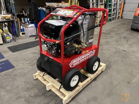 A red 2024 Magnum 4000 Hot Water Pressure Washer with a sturdy frame wheels and various controls and hoses on a wooden pallet