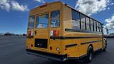 A yellow 2014 Freightliner Thomas diesel school bus with large windows and a black stripe along the middle