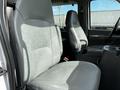 Front seats of a 2004 Ford Econoline with gray upholstery and a console between them