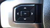 A close-up of a black control button panel featuring an ‘OK’ button in the center and directional arrows arranged around it