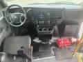 Interior view of a 2017 Chevrolet Express showing the driver's seat dashboard and controls with a red bag on the floor and a fire extinguisher in the cabin