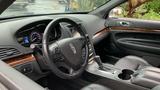 Interior of a 2013 Lincoln MKT featuring a black leather steering wheel dashboard with digital speed display and wood trim accents