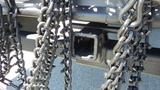 Close-up of a metal trailer hitch with heavy chains attached hanging down from it